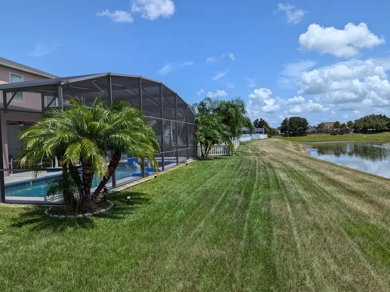 Mowing stripes sweeping past a screened pool cage toward the water