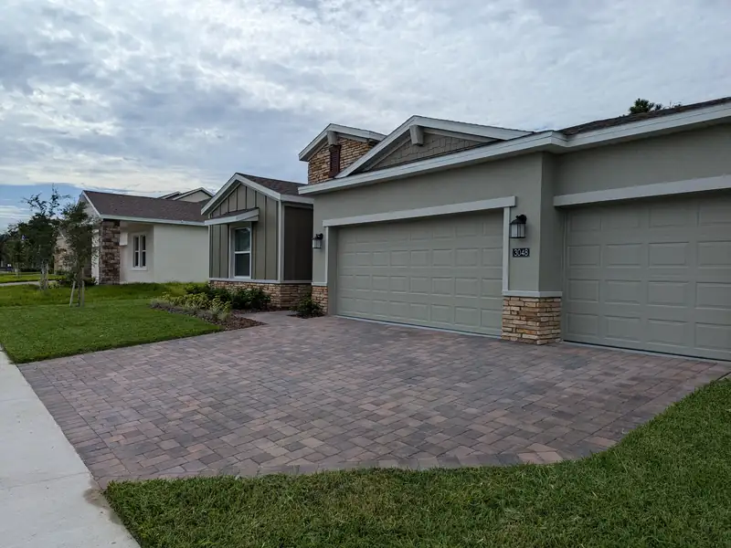 Clean mowed edge running alongside a paver driveway and garage