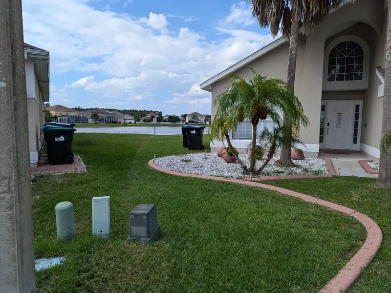 Lakefront lawn with trimmed palm bed and a clear walkway edge